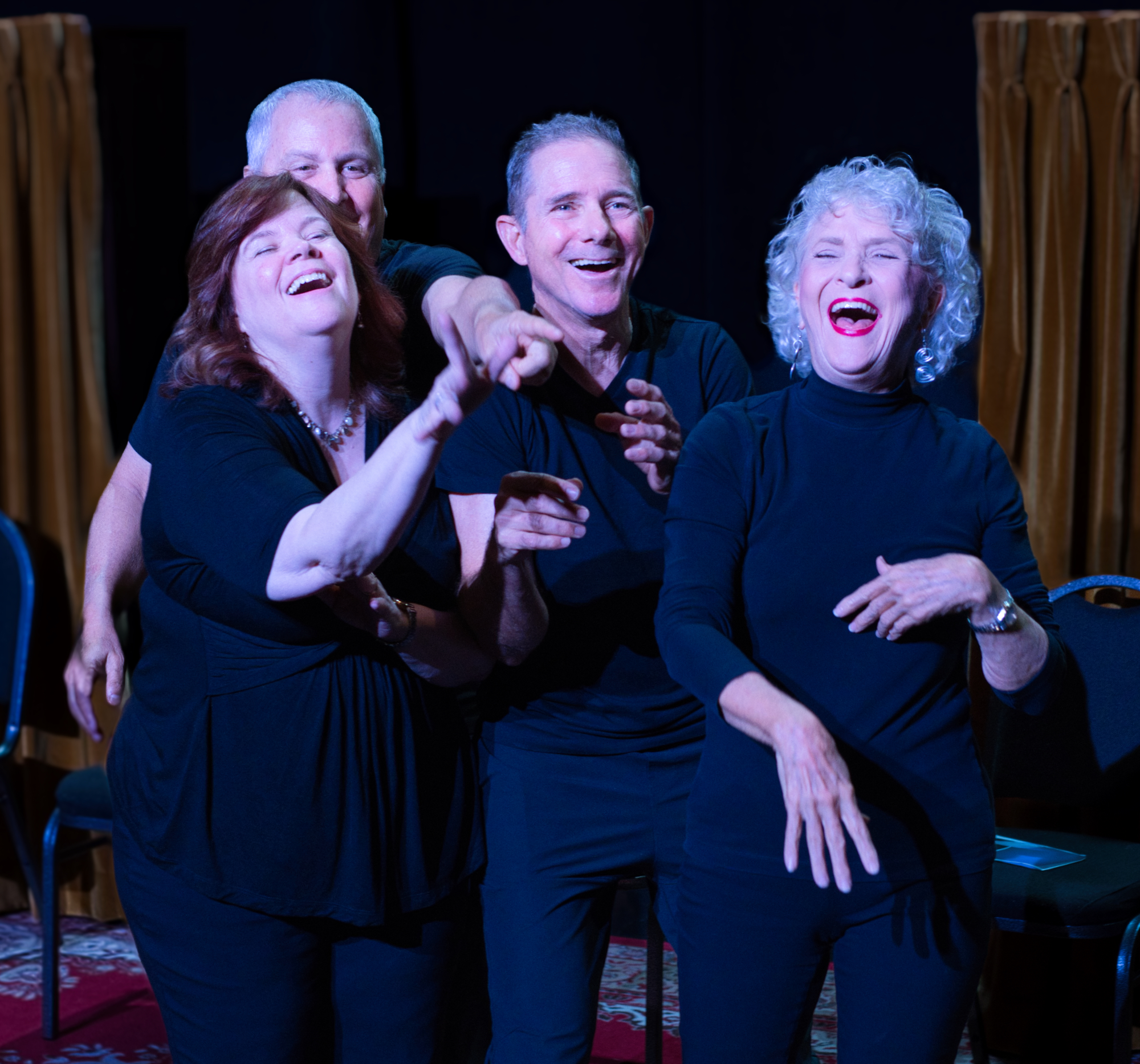 Performers laughing together on stage under warm light