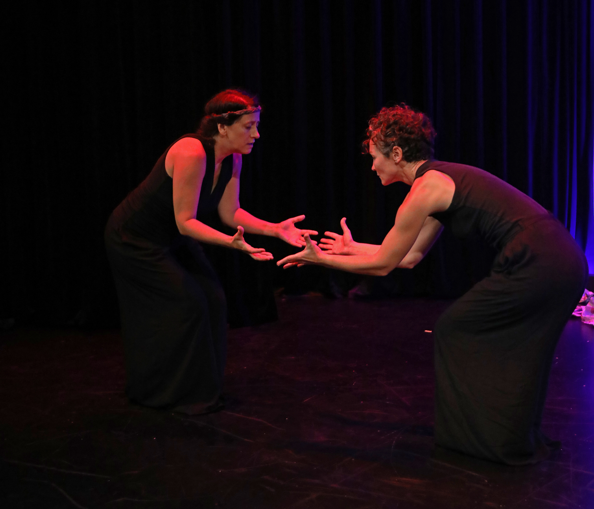Reaching hands extended upward on a dark stage